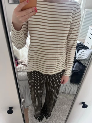 Beige och vit randig långärmad topp - Säljer en beige och vit långärmad topp med smala horisontella ränder. Toppen har en rak passform och rund halsringning. Perfekt att styla med jeans eller kjol för en enkel och snygg look.