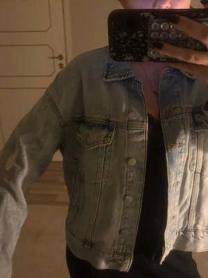 Ljusblå croppad jeansjacka - Säljer en ljusblå croppad jeansjacka med klassisk krage och knappar framtill. Jackan har två bröstfickor med lock och knapp, samt en avslappnad passform som ger en cool och trendig vibe. Perfekt att slänga över en hoodie eller t-shirt.💕