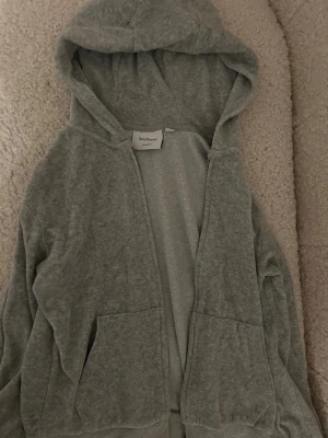 Grå Juicy Couture hoodie med dragkedja - Mysig grå hoodie från Juicy Couture med huva och dragkedja framtill med klassisk broderad JC-logga på bröstet. I storlek XXS men passar XS/S också!💞Endast använd ett fåtal gånger