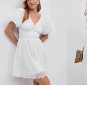 Vit kort klänning med puffärmar - Superfin vit kort klänning med v-ringning och puffiga kortärmar. Klänningen har en rosett i midjan, luftig kjol i ett tunt tyg. Perfekt till studenten! Säljer dö jag köpt en annan. Klänningen är aldrig använd☺️ 