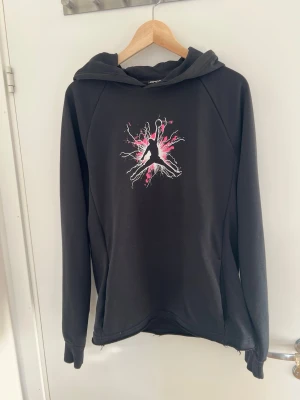 Svart Jordan set med rosa tryck - Säljer ett svart Jordan set med hoodie och byxor. Hoodien har ett coolt rosa och vitt tryck med Jumpman-loggan på bröstet och byxorna har matchande rosa detaljer och logga. Perfekt för dig som gillar streetwear och sportig stil.  Knappt använda, säljer eftersom jag inte använder det längre, mycket bra skicka inga defekter, tveka inte att skriva vid funderingar 🤝