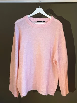 Ljusrosa stickad tröja  - Mysig ljusrosa stickad tröja från H&M med avslappnad passform och rund halsringning. Tröjan har långa ärmar och ribbade muddar vid ärmslut och nederkant. Perfekt för lager på lager och enkel att styla till olika looks. Köpt från Lager 157, använts en gång🌸