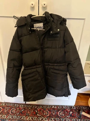 Svart dunjacka från Ganni med huva - Snygg svart dunjacka från Ganni med stor huva och dragkedja framtill. Jackan har två stora fickor med dragkedja . Den är xxs men oversized så passar xs. Jag har alltid xs och den passar mig perfekt 