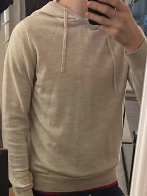 Beige hoodie cashmere  - Säljer en stilren beige hoodie med huva cashmere . Hoodien har långa ärmar och ribbade muddar vid ärmslut och nederkant. Tillverkad i ett mjukt och tunt material som känns skönt mot huden. Perfekt för dig som gillar en clean och enkel look.