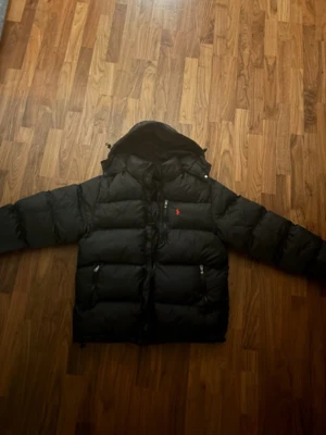 Svart pufferjacka från Polo Ralph Lauren - Jag säljer denna fina jacka då jag köpte fel storlek men inte kan skicka tillbaka jackan, Det är storlek M perfekt för folk i 13-15 års åldern, Den är aldrig använd och precis som ny