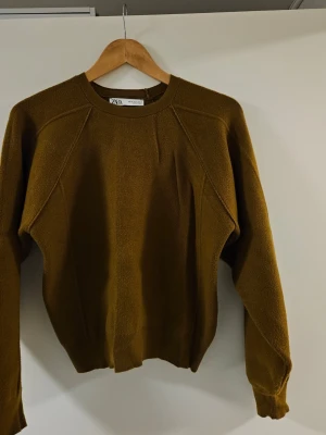 Brun stickad tröja från Zara - Säljer en enkel och stilren brun stickad tröja från Zara. Tröjan har rund halsringning, långa ärmar och en rak passform. Perfekt för lager på lager och höstiga outfits.