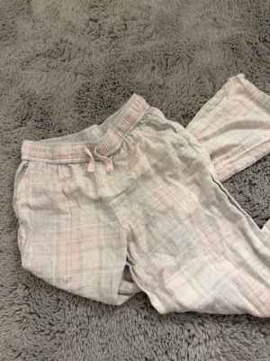 Rosa gråa rutiga pyjamasbyxor  - Ett par lågmidjade pyjamasbyxor som är rosa-gråa rutfärgade. Osäker på storlek och märke då lappen är bortklippt men passar nog någon runt 150. Säljer för att de är för små. De är ganska tvättade men inga hål eller liknande. 💕