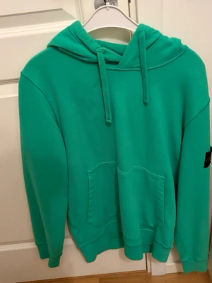 Grön hoodie med magficka - Snygg grön hoodie med klassisk magficka och dragsko i huvan. Hoodien har en avslappnad passform och ribbade muddar vid ärmslut och nederkant. Perfekt för en chill och bekväm stil.