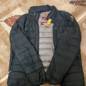Parajumpers M - Säljer en svart dunjacka från Parajumpers i storlek M. Jackan har quiltad design, grått foder och cool gul detalj vid halsen. Märkespatch på ärmen och dragkedjor på fickorna. Perfekt för dig som vill ha en snygg och funktionell jacka med streetvibe. Jackan är skadad på högra armen