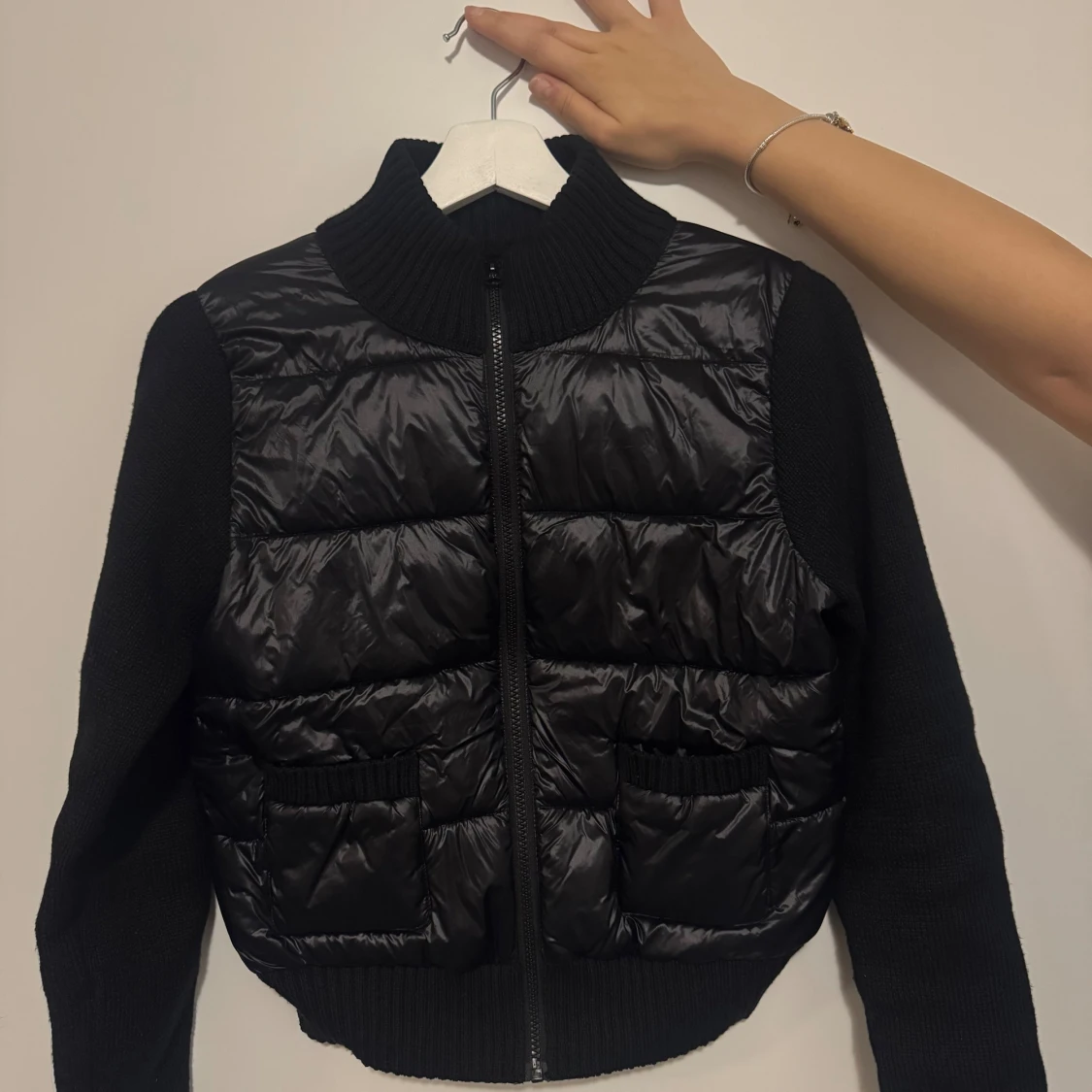 Svart pufferjacka med stickade ärmar