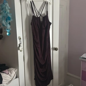 Vinröd långklänning från Bik Bok - Säljer en vinröd långklänning från Bik Bok med tunna korsade axelband och draperad effekt framtill. Klänningen har en elegant, figurnära passform och är tillverkad i ett glansigt material som ger en lyxig känsla. Perfekt för dig som vill sticka ut med en stilren look. Skit snygg festklänning som jag inte använder, köpte för en maskerad och legat i garderoben sen dess 😅☺️ Använd 1 gång 🥰