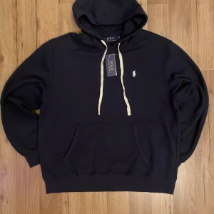 🔵 Mörkblå Polo Ralph Lauren Hoodie -  Snygg mörkblå hoodie från Polo Ralph Lauren – helt ny med taggar. Tidlös design med vit broderad logga på bröstet. Perfekt basplagg för alla tillfällen.  💰 Pris: 649kr 📦 Fraktas snabbt 