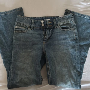 Blå jeans från Cubus, storlek 158 - Snygga blå jeans från Cubus i klassisk modell med raka ben och dubbla knappar i midjan. Jeansen har coola fickdetaljer med knappstängning och slitningar som ger en avslappnad vibe. Perfekt passform och sköna att bära hela dagen.