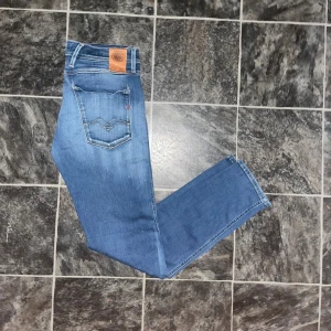 Replay Anbass hyperflex jeans  - Säljer ett par Replay Anbass hyperflex jeans i snyggt blått och klassiska fem fickor. Jeansen har en slim fit-modell. JAG SKICKAR EJ FLER BILDER NÄR JAG BÄR JEANSEN! för storleksguide hänvisar jag till måtten och för bättre inblick i passformen rekommenderar jag att googla på modellnamnet. Jeansen kan vara uppsydda utan att jag noterat det så kolla måtten noggrant :) Midja 39cm, längd 100cm. OBS se defekten på sista bilen. 37