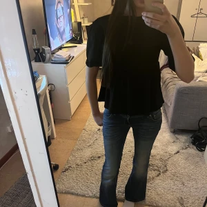 Svart blus med knyt  - Svart blus med volang nedtill och puffiga trekvartsärmar. Toppen har två snygga knyt framtill/bak, beroende på hur man har den, som ger en cool detalj. (Aldrig använd❤️)