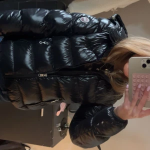 Colmar jacka - Säljer en svart, glansig pufferjacka från MooRER med huva och två dragkedjefickor. Jackan har quiltad design och en rund logotyp på ärmen. Perfekt för kalla dagar och har en snygg, modern look. Den är i storlek 156 motsvarar XXS. Den är i fint skick . SKRIV FÖR FLRR BILDER!🥰🥰 priset kan diskuteras.