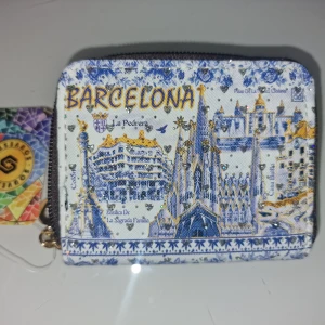 Barcelona plånbok med glittrigt tryck - Plånbok med Barcelona-motiv i blått, vitt och gult. Framsidan har detaljerade illustrationer av stadens kända byggnader och glittriga accenter.  