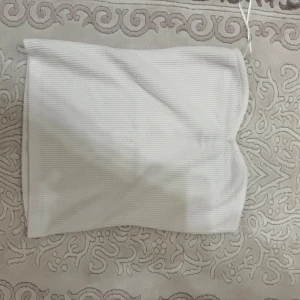 Vit ribbad tubtopp från Stockh LM Studio - Säljer en fräsch vit tubtopp från Stockh LM Studio i storlek XS. Toppen är ribbad och har en enkel, stilren design som sitter snyggt och är perfekt för varma dagar. Materialet känns mjukt och bekvämt mot huden. Perfekt att styla med jeans eller kjol.