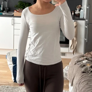 Vit långärmad topp med rund hals - Säljer en enkel och stilren vit långärmad topp med rundad halsringning. Modellen är figurnära och har en mjuk känsla, perfekt att styla med jeans eller kjol. Materialet känns lätt och bekvämt mot huden.
