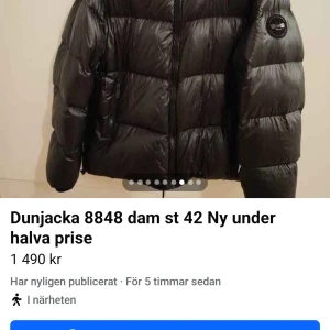 Svart dunjacka från 8848 Altitude - Snygg svart dunjacka från 8848 Altitude i storlek 42. Jackan har quiltad design, dragkedja framtill och praktiska fickor med dragkedja. Perfekt för kalla dagar och har en modern, puffad look med långärmade ärmar och diskret logga på axeln.