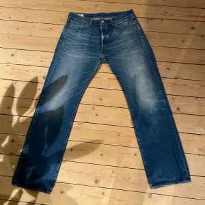 Levi's 501 150th - Klassiska Levi's 501 jeans i blå tvätt med raka ben och normal passform. Jeansen har fem fickor, knappgylf och den ikoniska läderpatchen bak i midjan. Materialet är slitstark bomullsdenim med snygga slitningar framtill.
