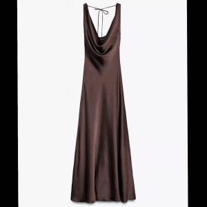Brun långklänning i satin med öppen rygg - Supersnygg brun långklänning i glansig satin med draperad urringning och öppen rygg som knyts med tunna band. Midilängd. Perfekt för sittning. Prislapp kvar, aldrig använd. Nypris 700.