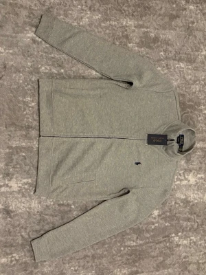 Grå ralph lauren hel zip - Säljer en hel grå zip ralph Lauren som är i helt ny skick utan användning. Ettitket finns även på.