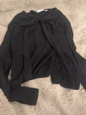 Svart stickad kofta med knyt - Mysig svart stickad kofta med långa ärmar och knytband framtill. Perfekt för lager på lager och enkel att styla till olika outfits. Koftan har en klassisk look och är superbekväm.