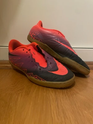 Nike Hypervenom X fotbollsskor 38.5 - Säljer ett par Nike Hypervenom X fotbollsskor i storlek 38.5. Skorna har en cool färgkombo med lila, svart och neonorange samt grafiskt mönster på sidorna. Yttersulan är gummibrun med Nike-logga undertill. Perfekta för inomhusfotboll och har platt sula.