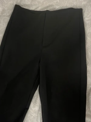 Svarta kostymbyxor Gina Tricot - Stilrena svarta kostymbyxor från Gina Tricot i storlek 32. Byxorna har en rak passform med slits vid benslutet och är tillverkade i ett mjukt, vävt material. Perfekta till en snygg och clean look.