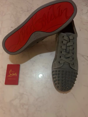 Gråa Christian Louboutin  - Säljer ett par gråa sneakers Christian Louboutin, helt nya och oanvända. Priset kan diskuteras.