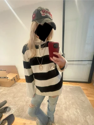 Randig stickad tröja från Divided H&M - Säljer en ribbstickad tröja från Divided H&M i storlek S. Tröjan har breda svarta och vita ränder, hög krage och långa ärmar. Superbra skick