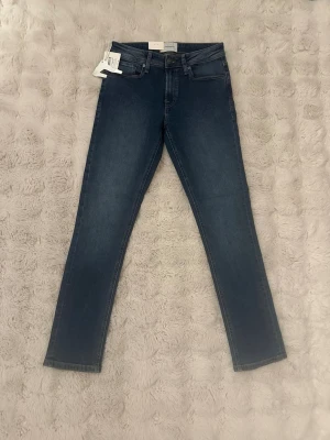 Slim jeans denim TeeShoppen - Slim fit jeans från TeeShoppen i en snygg mellanblå tvätt. Klassisk femficksmodell med raka ben och normal midja. Tillverkade i mjuk och stretchig denim för skön passform. Perfekta till sneakers eller boots.