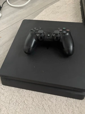 PlayStation 4 med handkontroll och spel - Sony PlayStation 4 i gott skick med en original handkontroll. Flera populära spel, bl.a. The Last of Us Remastered, Star Wars Jedi: Fallen Order, Crash Bandicoot, FIFA och GTA V. Perfekt för spelkvällar! Mindre bruksspår kan förekomma.spelen kommer inte med men du kan välja vilken som du vill ha med. 