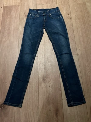 Levi's 511 blå jeans, midwaist - Säljer ett par klassiska Levi's 603 jeans i mörkblå tvätt. (W26 L32)Modellen har rak passform med något smalare ben, fem fickor och snygga kontrastsömmar. Jeansen har midwaist och är tillverkade i slitstarkt denim med dragkedja och knapp framtill.