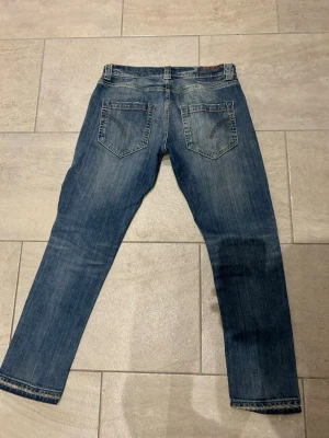 Blå slim fit jeans dondup - Snygga blå jeans från dondup slim fit-modell. Klassisk femficksdesign med slitningar och ljusare partier på låren för en cool, använd look. Jeansen har normal midja och raka ben, perfekta till sneakers eller boots. Jeans passar någon som bär 32/32