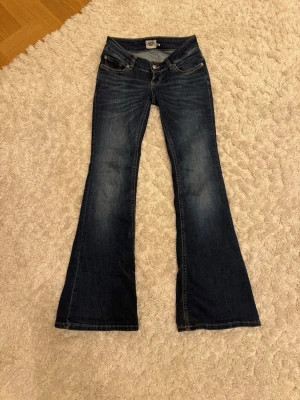 Mörkblå jätte lågmidjade bootcut jeans från 157 - Snygga mörkblå bootcut jeans från 157 med klassisk femficksdesign och slitningar vid bensluten. Jeansen har låg midja och är tillverkade i ett robust denimtyg. Perfekta för dig som gillar retrovibbar och vill ha ett par jeans med riktigt schysst passform. !PRISET KAN DISKUTERAS!