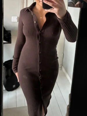 Brun ribbad långklänning med knappar - Säljer en brun, ribbad långklänning med lång ärm och knappar hela vägen framtill🤎