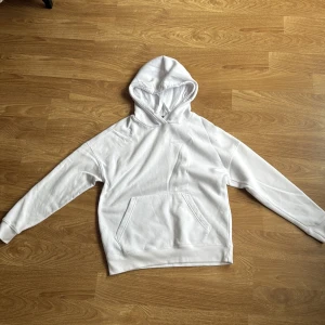 Vit hoodie från FB Sister i XXS - Säljer en basic vit hoodie från FB Sister i storlek XXS. Tröjan har huva, magficka och långa ärmar. Perfekt för dig som gillar en enkel och clean stil. Materialet är mjukt och skönt, troligtvis bomullsmix. Snygg att matcha med jeans eller joggers.