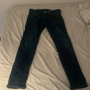 Replay Anbass Slim Fit Jeans Blå - Säljer ett par snygga Replay Anbass slim fit jeans i mörkblå tvätt. Jeansen har klassisk femficksdesign, smal passform och är tillverkade i mjukt bomullsmaterial med stretch. Perfekta för dig som gillar en stilren och modern look.