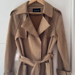 Beige trenchcoat från Stradivarius M - Snygg beige trenchcoat från Stradivarius i storlek M. Jackan har klassisk krage, stora fickor och bälte i midjan. Tillverkad i mjukt material med mockakänsla och långa ärmar. Perfekt för lager-på-lager och en clean look. Stor i storlek och kan passa L, bröst 110-112cm, hade på mig två gånger.