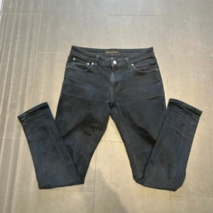 Nudie Jeans - Svarta Skinny Lin jeans från Nudie Jeans med tight passform. Jeansen är tillverkade i 98% bomull och 2% elastan för en stretchig känsla. Snyggt minimalistiska och passar perfekt till sneakers eller boots. Storleken är 31 | 30. Nypris 1599kr.