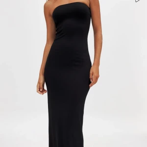 Svart axelbandslös långklänning - PRISLAPP KVAR!Säljer en svart, axelbandslös långklänning med slim passform. Klänningen har en snygg slits bak och är figurnära hela vägen ner. Perfekt för dig som gillar minimalistisk och stilren design. Materialet känns mjukt och följsamt mot kroppen.