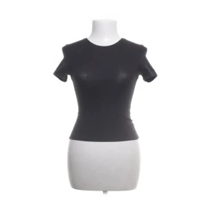 Svart tight topp från Weekday XS - En svart, tight topp från Weekday i storlek XS. Modellen är figurnära med korta ärmar och rund halsringning. Perfekt basic-plagg i mjukt bomullsmaterial som funkar till allt. Enkel och stilren design utan mönster eller detaljer.