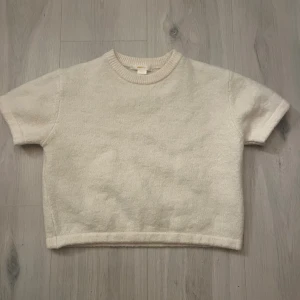 Beige stickad tröja från Gina Tricot - Supermjuk och enkel beige stickad tröja från Gina Tricot. Modellen är boxig med korta ärmar och ribbad rund halsringning. Perfekt för lager-på-lager och passar till allt. Snygg basic som funkar året runt.