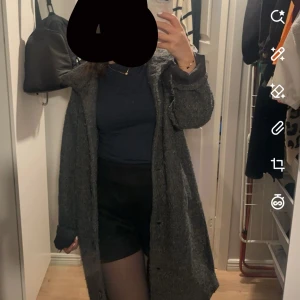 Grå lång kappa i ullmix - Säljer en snygg grå kappa med lång passform och klassisk krage. Stängs med knappar framtill.