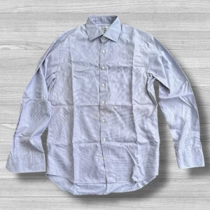 Ljusblå rutig skjorta från Stenströms - Snygg ljusblå skjorta från Stenströms med diskret rutigt mönster. Skjortan är i bomull, har klassisk krage, långa ärmar och knäppning framtill. Passformen är fitted body vilket ger en smalare siluett. Perfekt för dig som gillar stilrena detaljer.