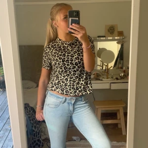 Leopardmönstrad kortärmad topp - Säljer en snygg kortärmad topp med leopardmönster i beige och svart. Modellen är croppad och har rund hals. Perfekt för dig som vill sticka ut med ett djuriskt print och gillar trendiga detaljer.