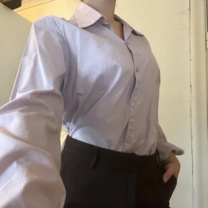 Ljuslila oversized skjorta - Snygg ljuslila skjorta med klassisk krage och knappar framtill. Modellen är oversized med långa ärmar. Perfekt att styla med jeans eller kostymbyxor för en chill och trendig look. Så svårt att få till färgen i kameran, är en blandning mellan bilderna i färgskala. Väldigt fin ljuslila! Tyvärr inte min stil därav säljs den, aldrig använd! 💜💜