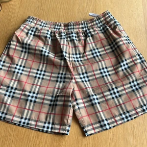 Rutig Burberry shorts - Snygga shorts från Burberry med klassiskt rutig mönster i beige, svart, vit och röd. 